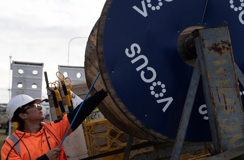 Picture of a Vocus worker with a very big coil of fibre cable.