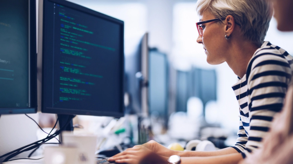 This is an image of an office worker at her PC looking at code.