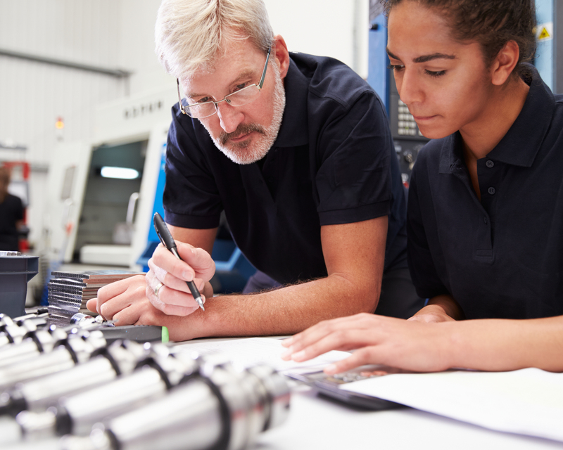 Two materials engineers partnering and working on plans at a desk 