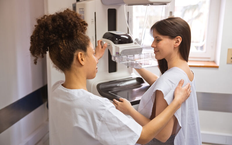 A woman talks with a nurse near mammogram equipment