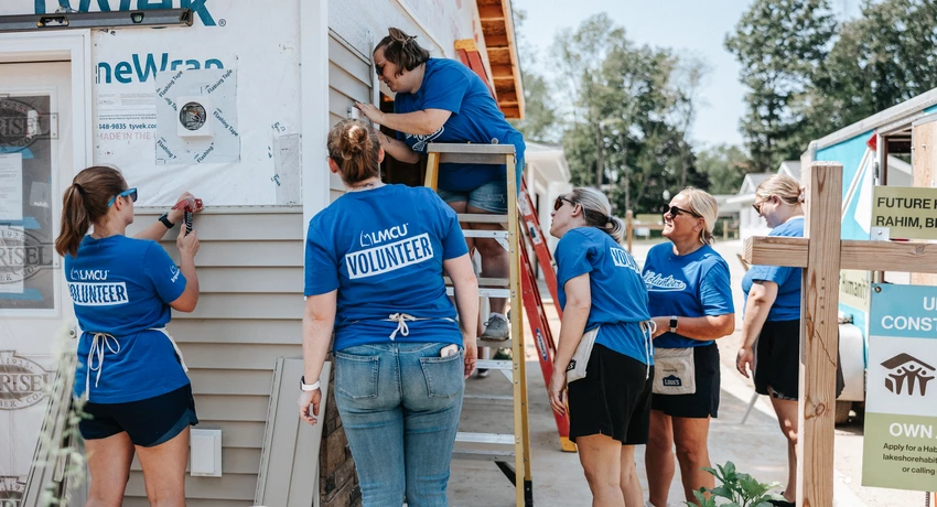 Group of LMCU employees outside working on construction of house 