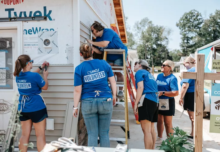 Group of LMCU employees outside working on construction of house 