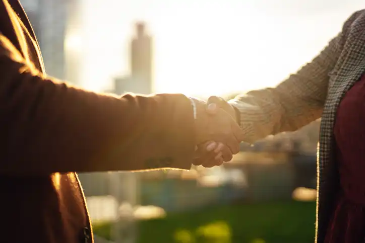 Two business leaders shaking hands against the backdrop of a city