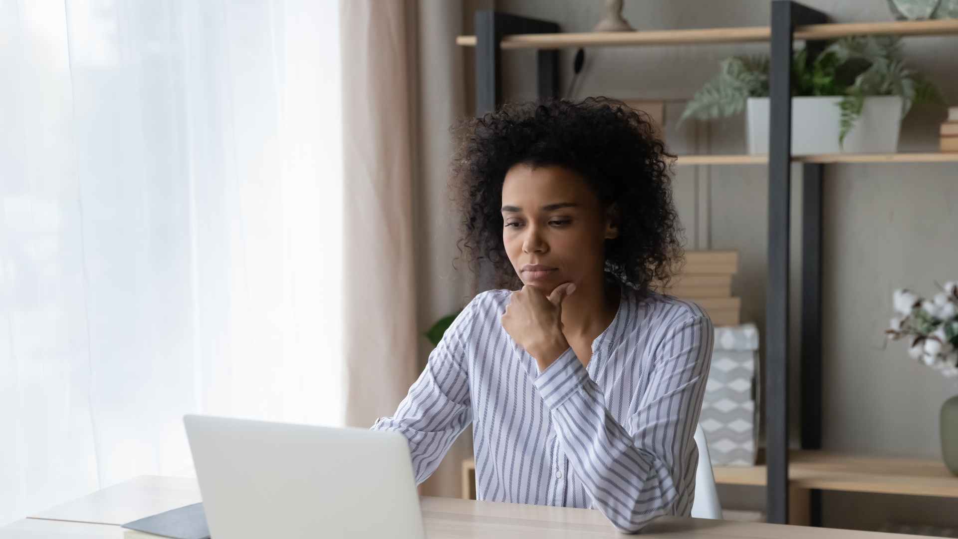 Pensive African American woman work on laptop online