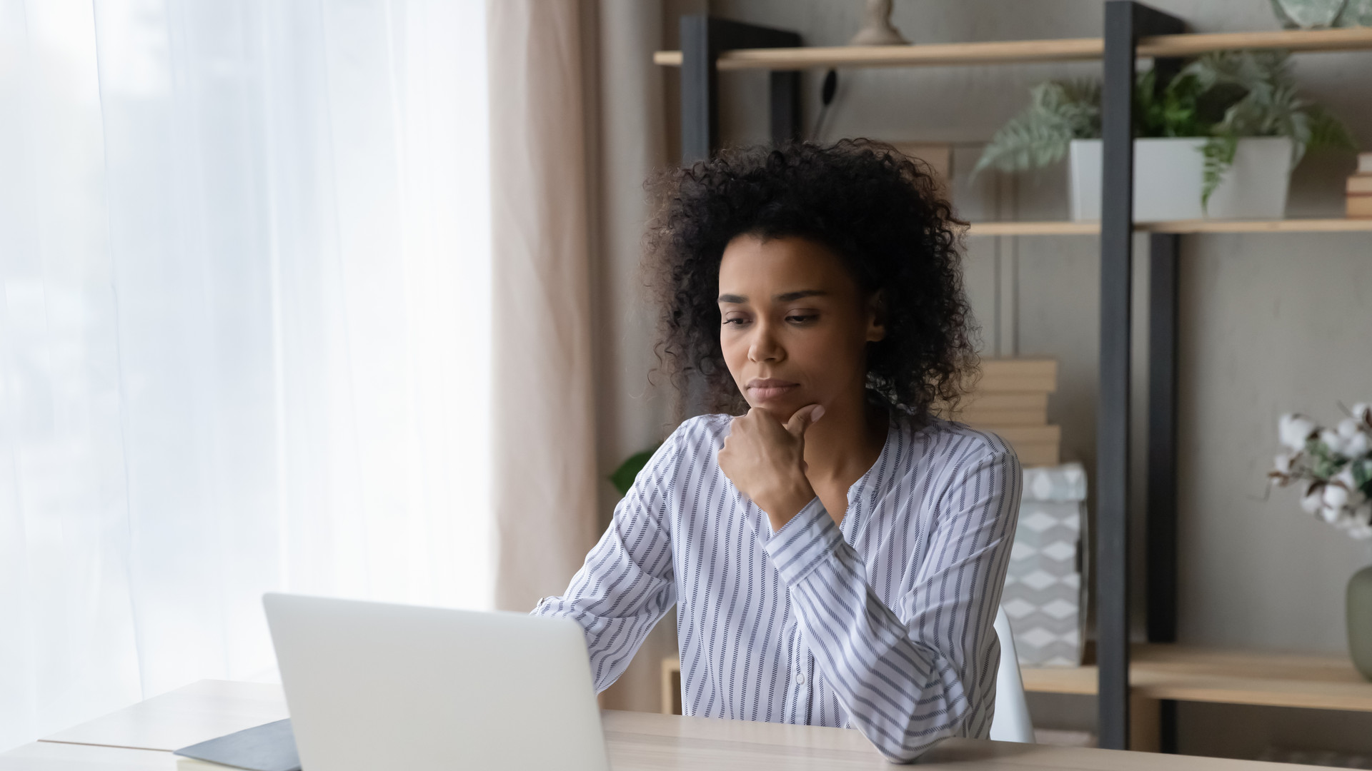 Pensive African American woman work on laptop online