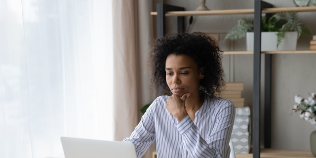 Pensive African American woman work on laptop online