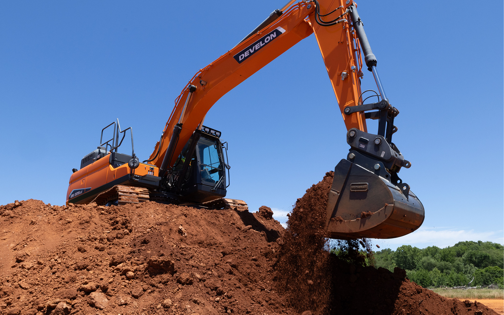 A DEVELON crawler excavator scoops dirt using a bucket.