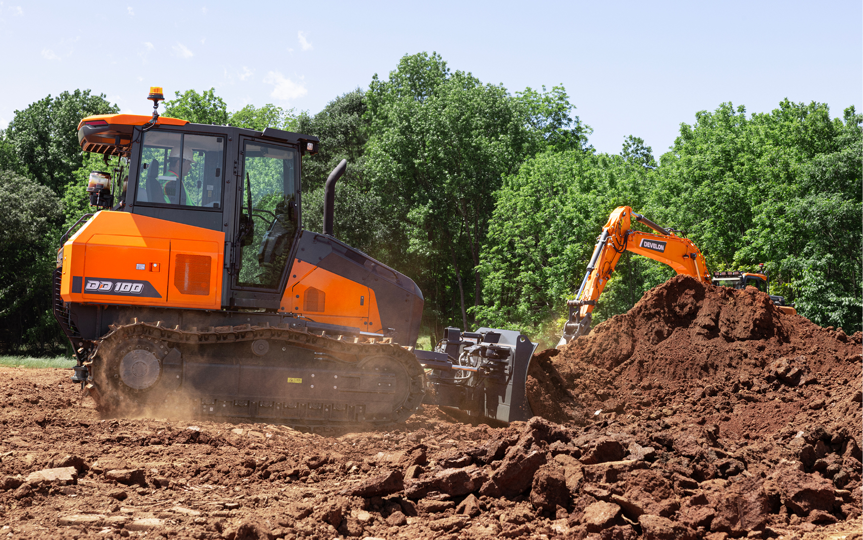 A DEVELON dozer uses the grading blade to push dirt.