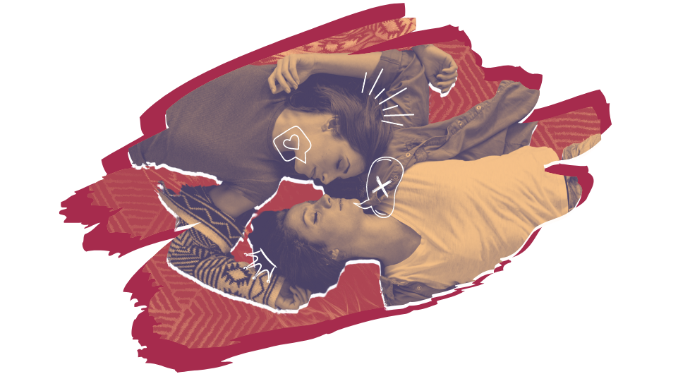 Two girls lying down together and looking at each other.