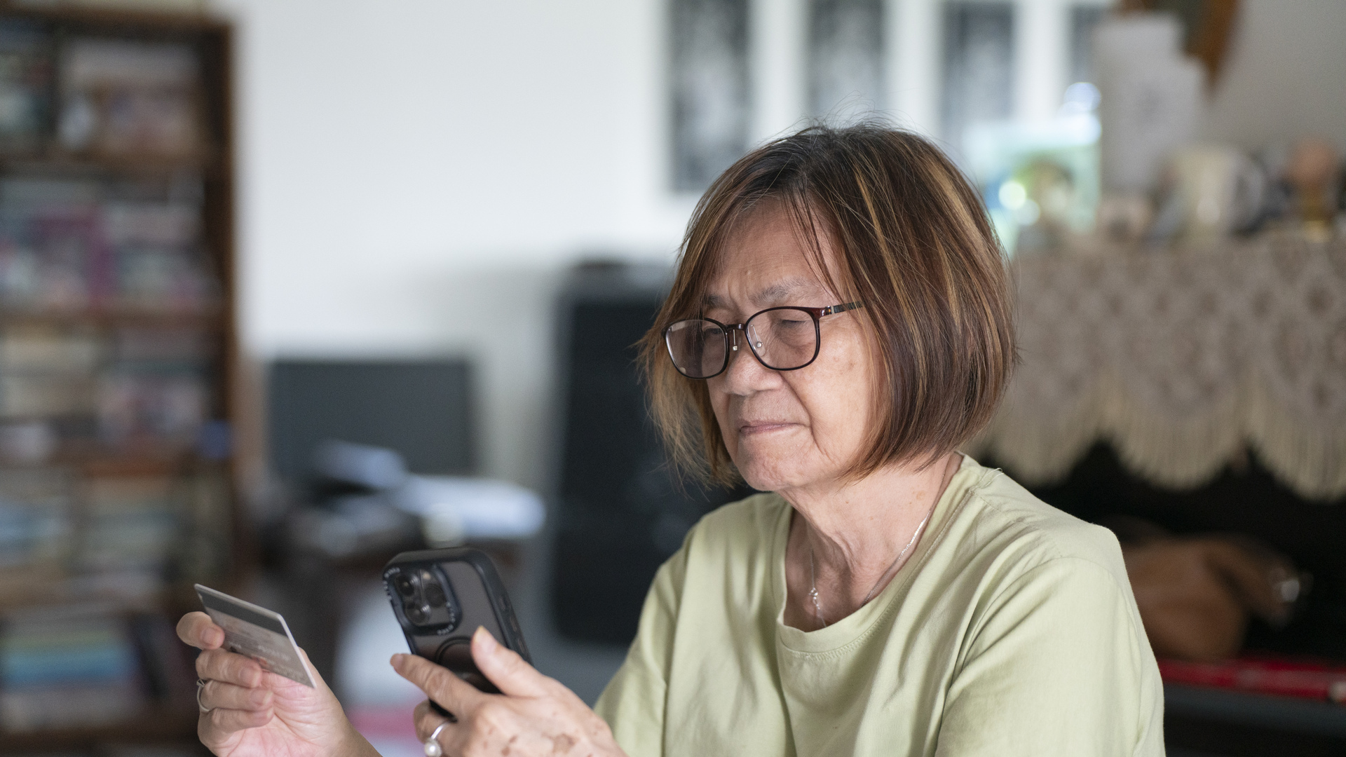 Elderly Singaporean woman giving credit card details to phone scammer
