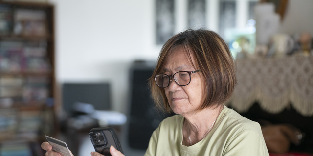 Elderly Singaporean woman giving credit card details to phone scammer