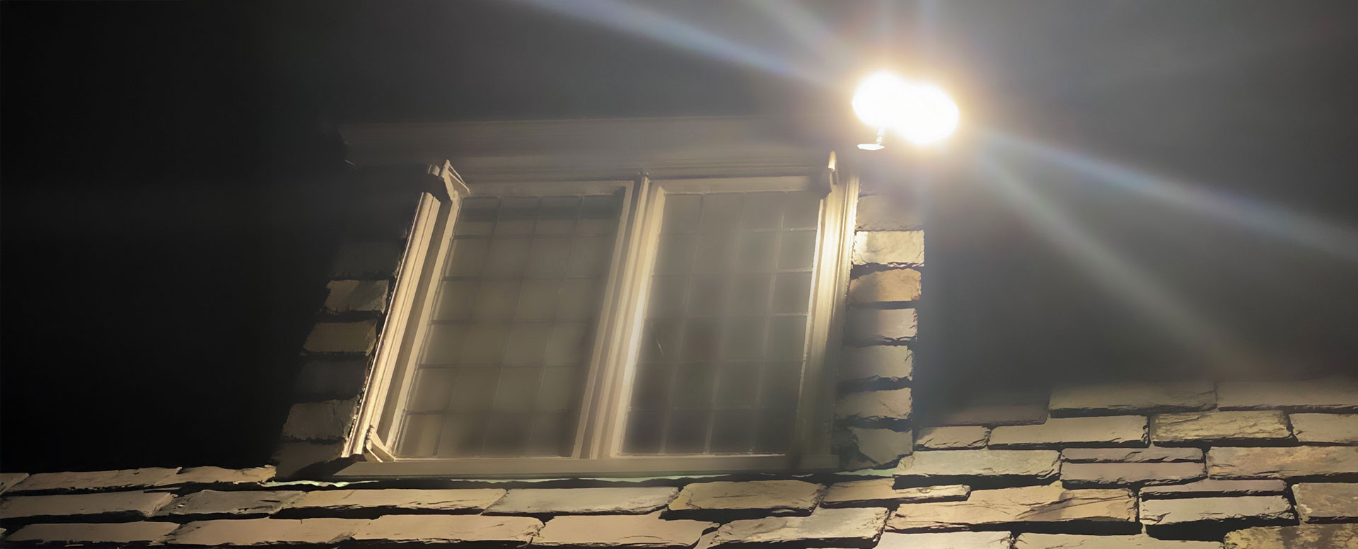A floodlight lights up the outside of a house.