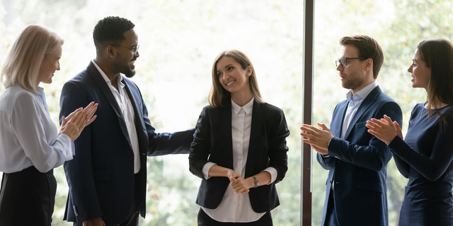 Multiracial colleagues applaud congratulating female leader with success