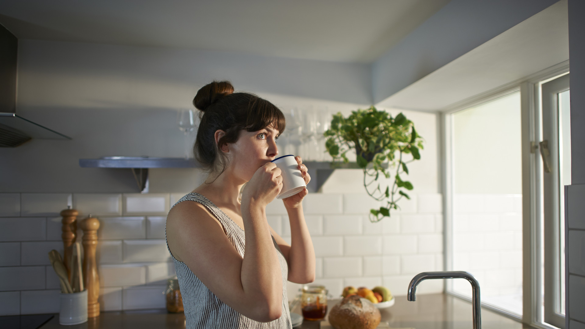 Woman drinking from mug in zero waste kitchen.