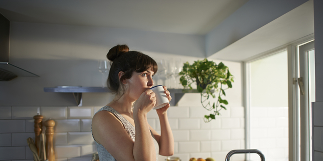 Woman drinking from mug in zero waste kitchen.