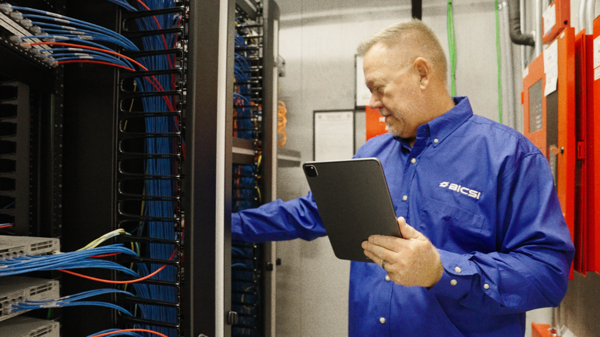 BICSI certified technician reviewing structured cabling installation specifications on a tablet in a data center server rack