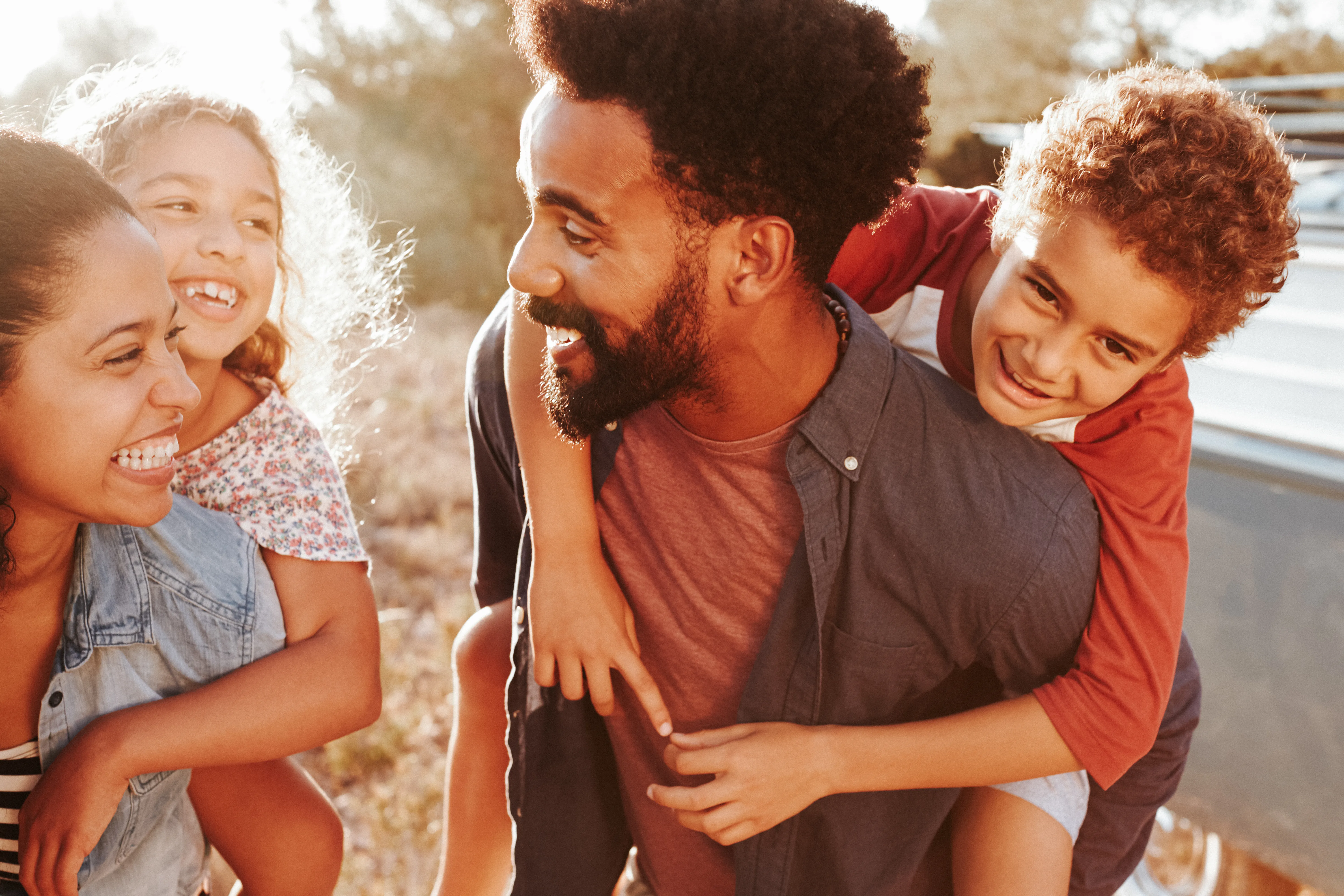 Parents giving their kids piggybacks, waist up, close up    