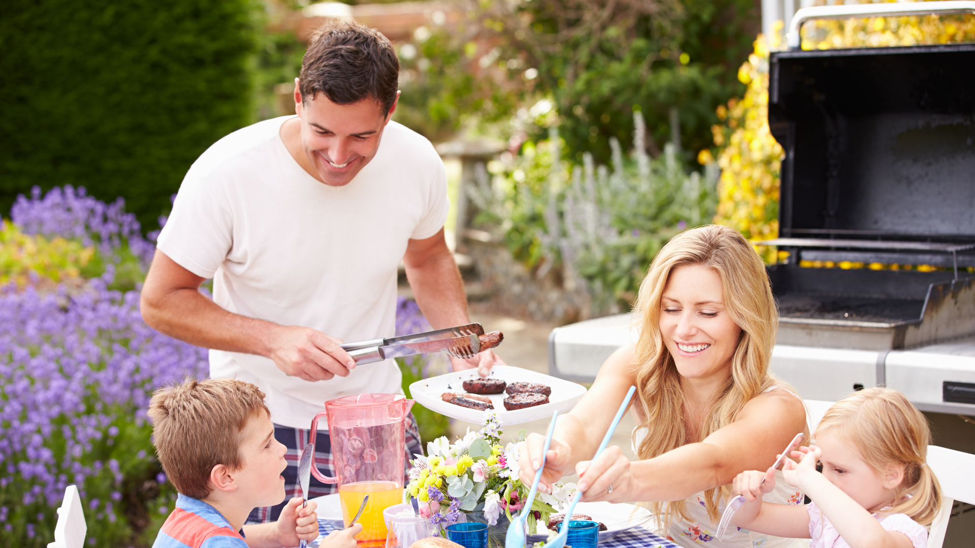 Family Enjoying Outdoor Barbeque In Garden