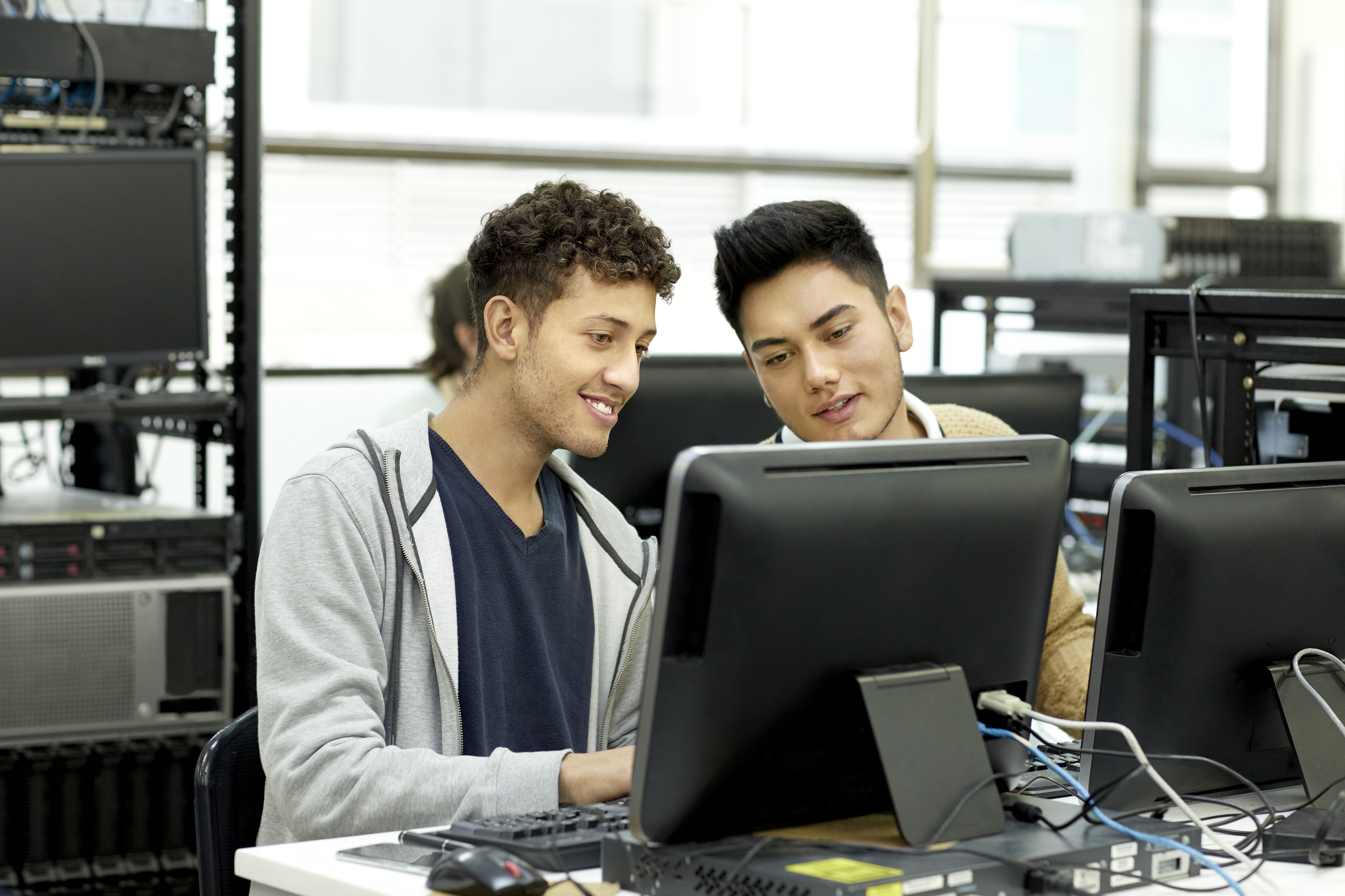 Two students in a computer lab use live production software for a student project.