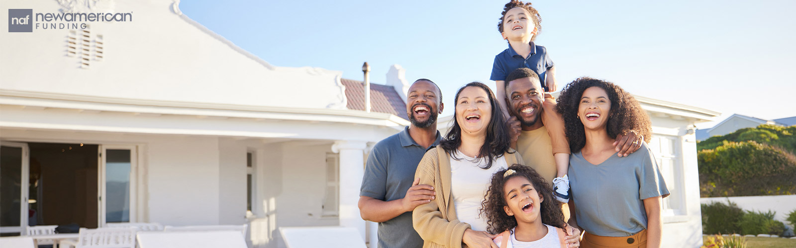 A happy mixed race family stands smiling in front of their home