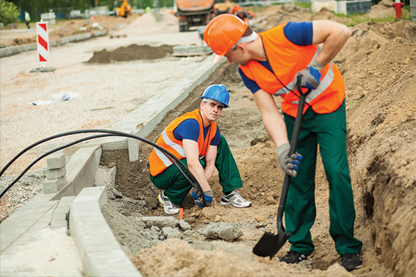 Technicians installing underground telecommunications cabling in a trench