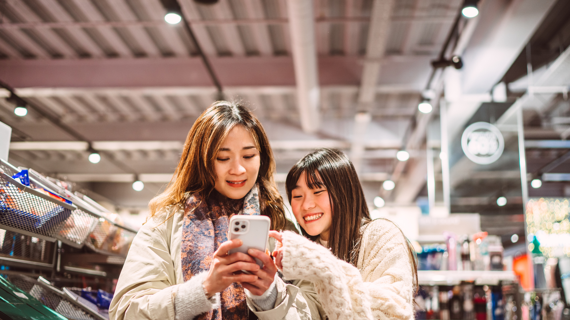 Mother and daughter shopping together using smart phone in store