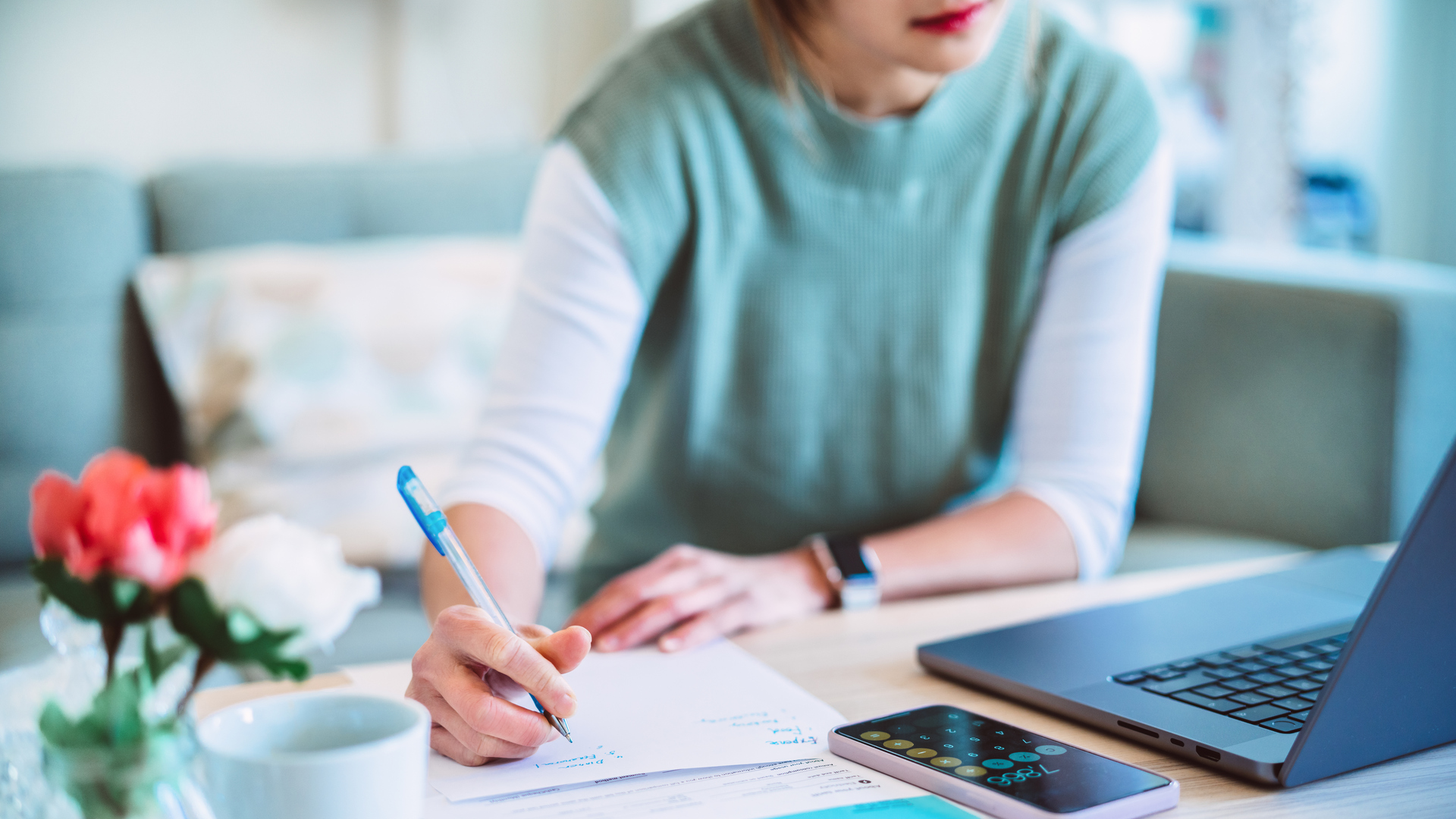 Young Asian women managing home finance using laptop & smartphone. She is working with household utility bill and calculating expenses at home.