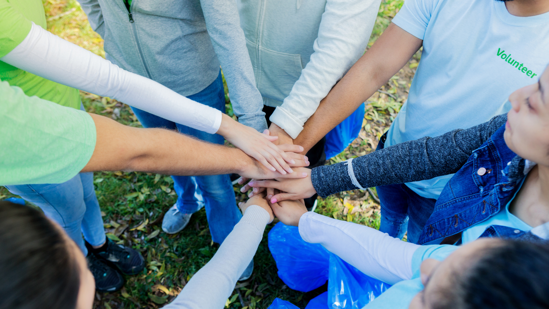 Group of unrecognizable volunteers stack hands before serving