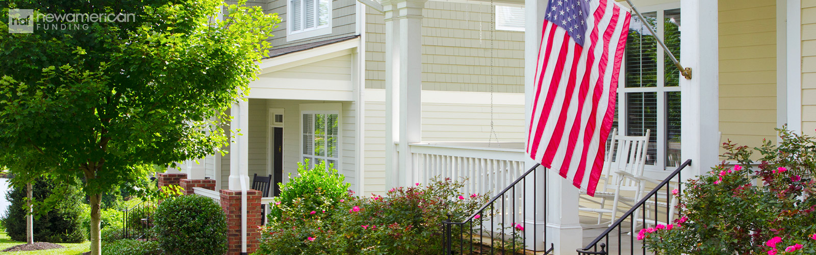 An American flag hangs from the porch of a nice vinyl-sided home