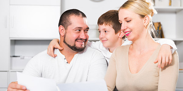 A white man, woman, and child sit at a table talking and smiling