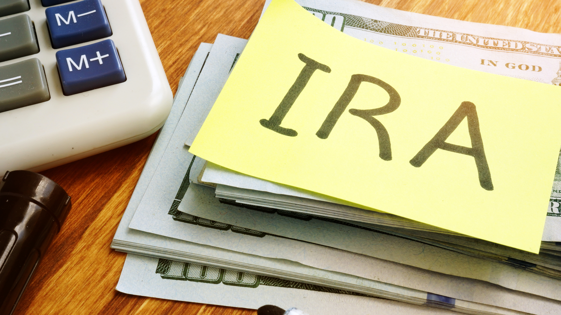 IRA individual retirement account. Stack of money and calculator.