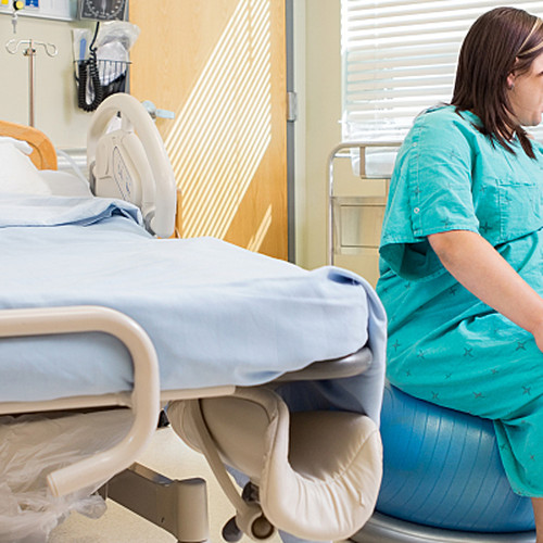 A pregnant patient sits on a rolling ball during labor to allow for movement as she talks with her partner.