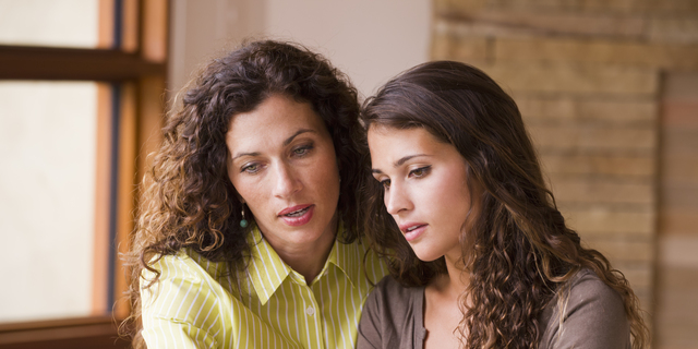 Mixed race mother and daughter using laptop together