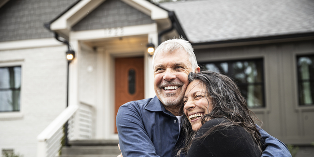 Portrait of senior couple in front of home