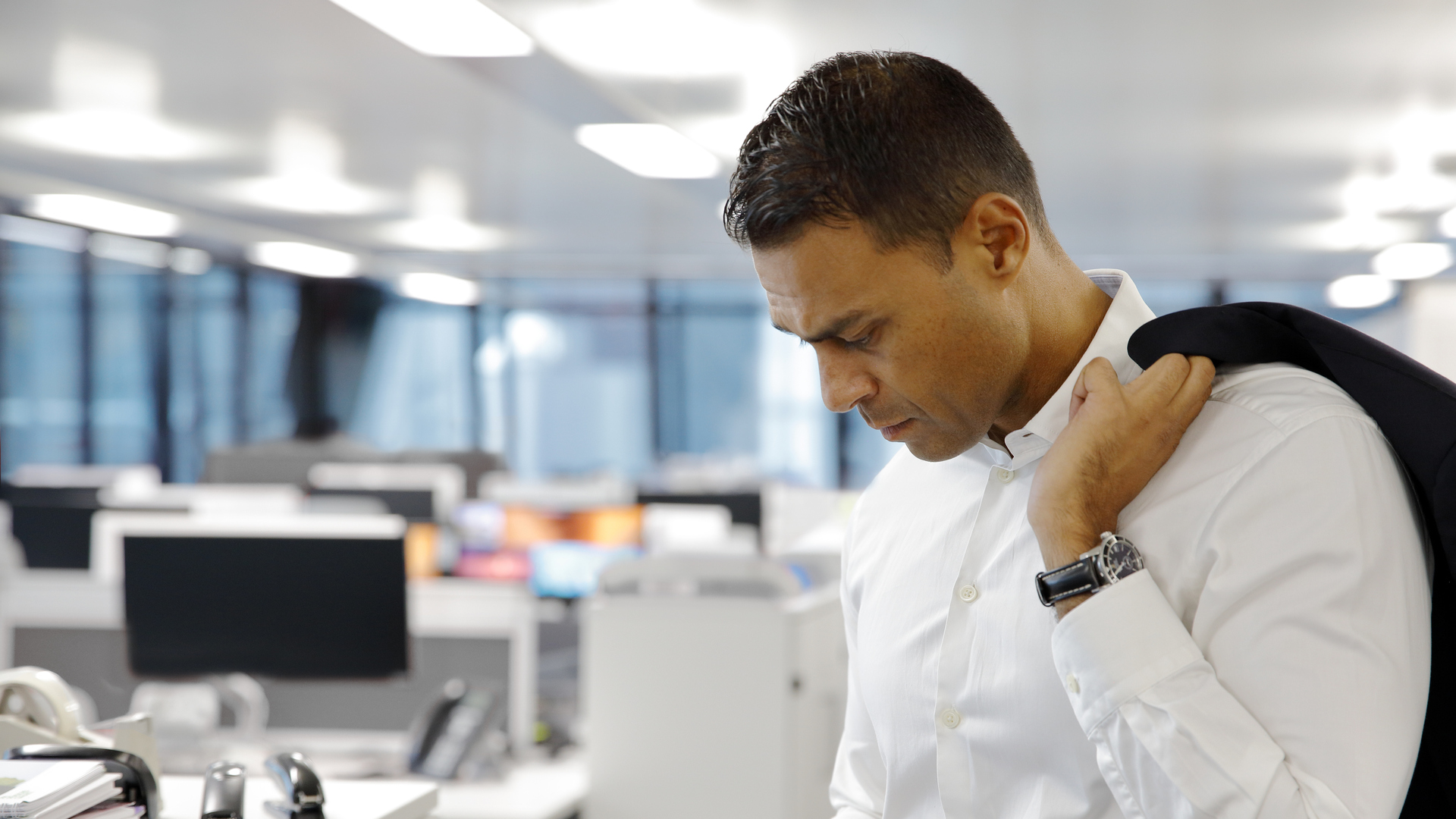 Casual businessman looking at smartphone in an empty office