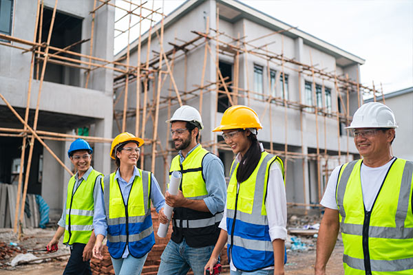 Construction workers wearing hard hats, safety glasses, and reflective vests at a building construction site