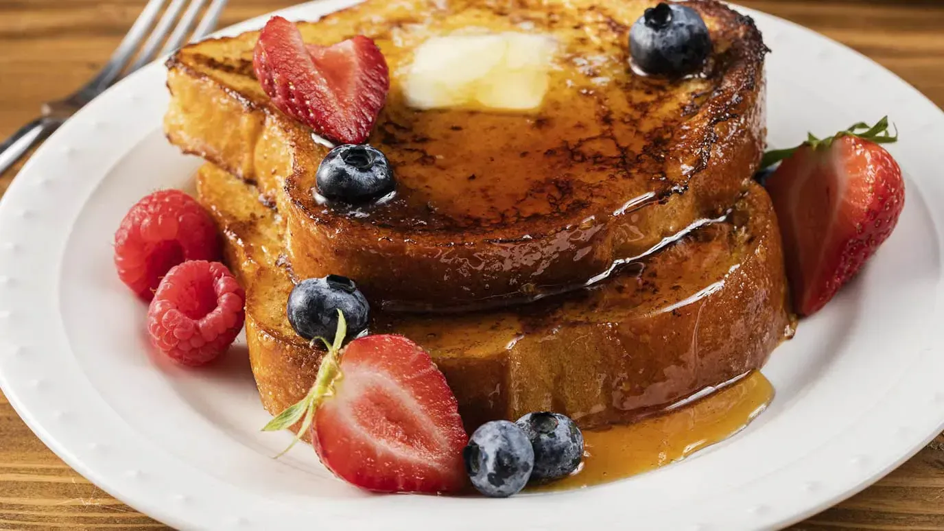 Plate of french toast with berries and syrup