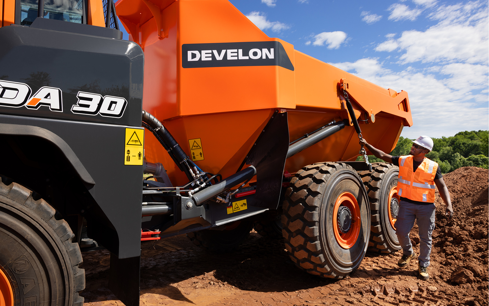 An operator inspects the outside of a DEVELON DA30-5 articulated dump truck.