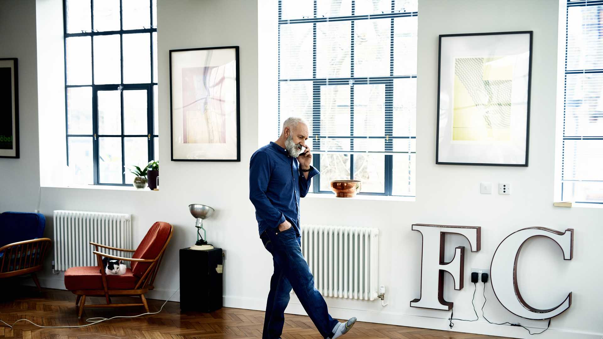 Hipster senior man on cell phone in funky apartment