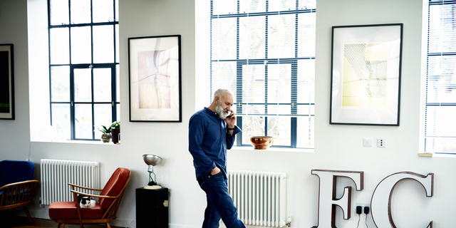 Hipster senior man on cell phone in funky apartment