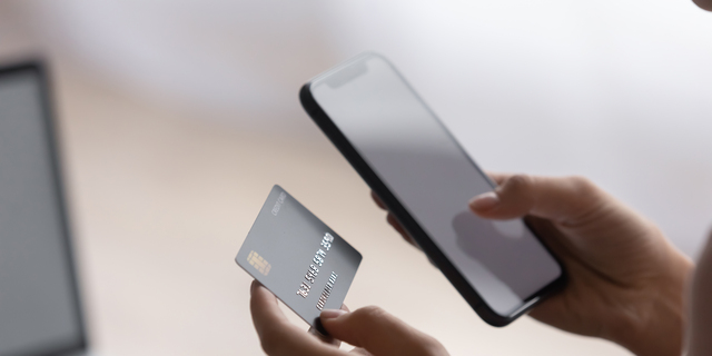 Female hands holding plastic card and cellphone purchasing goods online