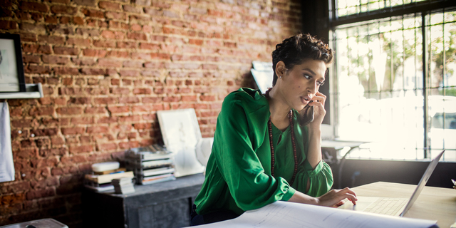 Businesswoman looking over architecture blueprints in office