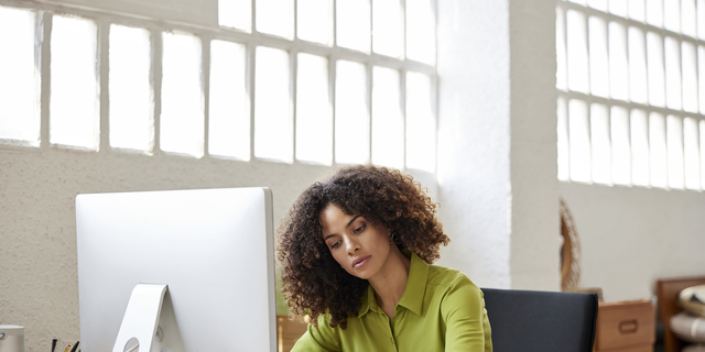 Businesswoman Writing On Document Sitting At Desk