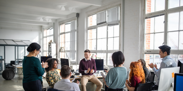 Business team clapping for a female colleague in meeting