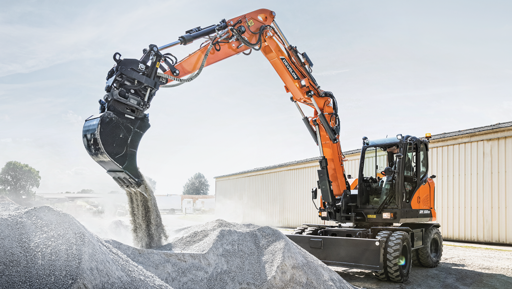 A DEVELON DX100W-7 mini wheel excavator dumps material on a jobsite.