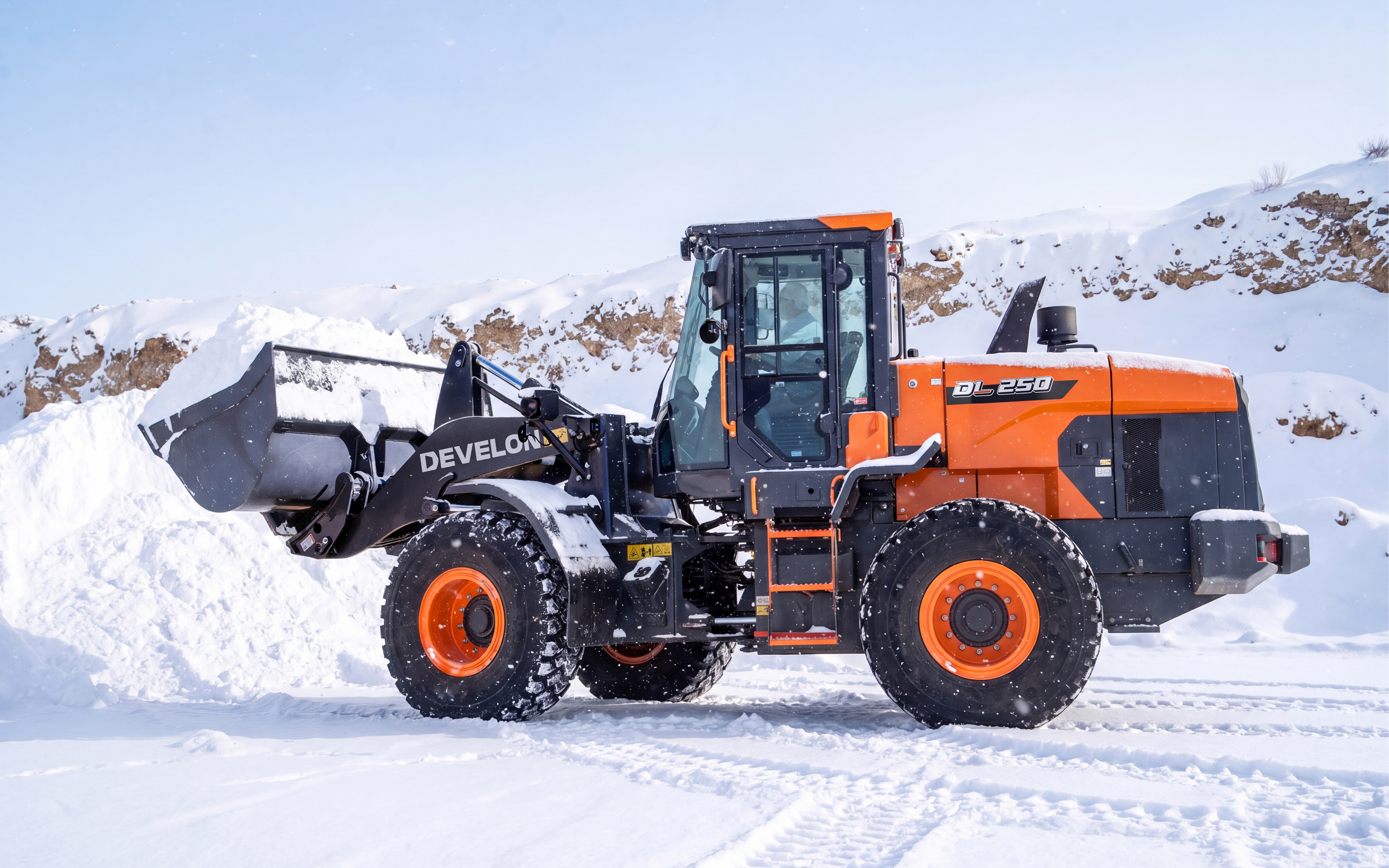 A DEVELON DL250-7P wheel loader hauling a bucket of snow after proper winter prep.