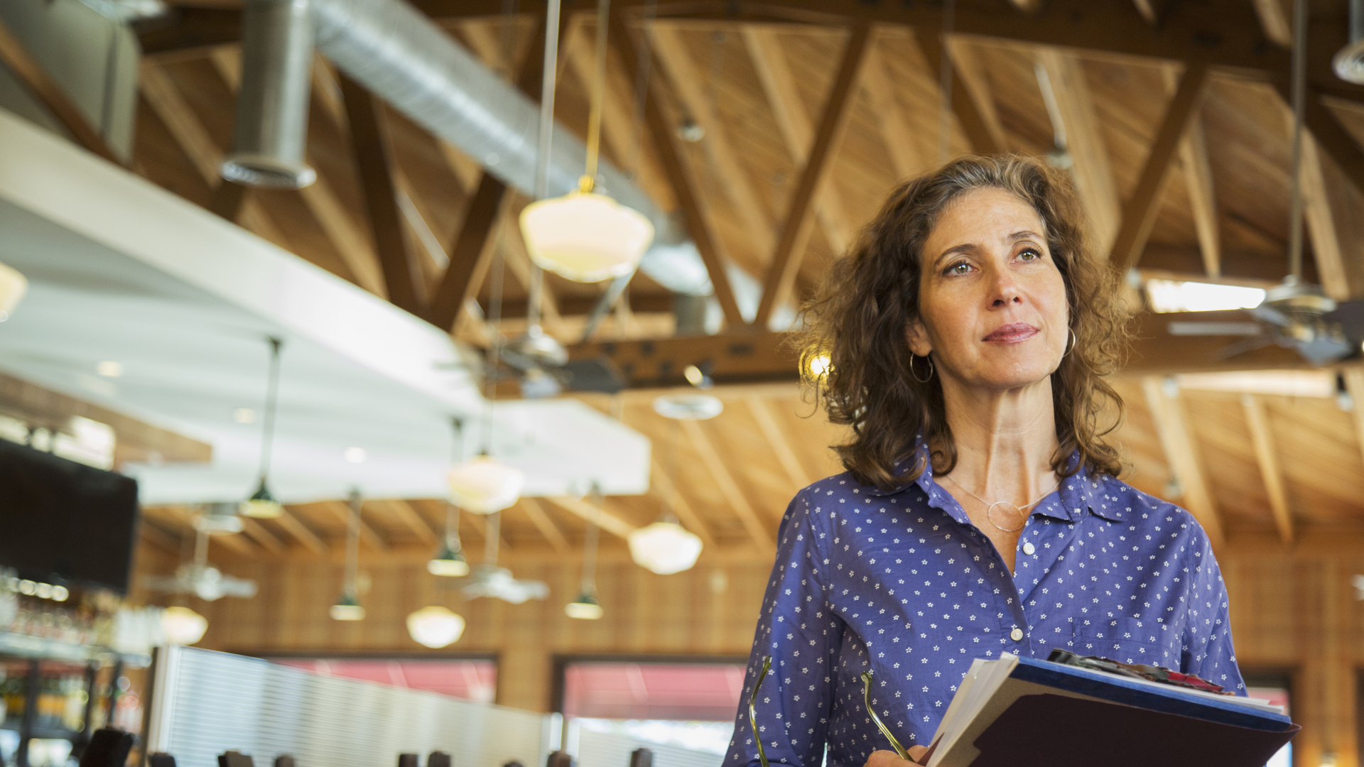 Pensive Caucasian woman holding paperwork in restaurant