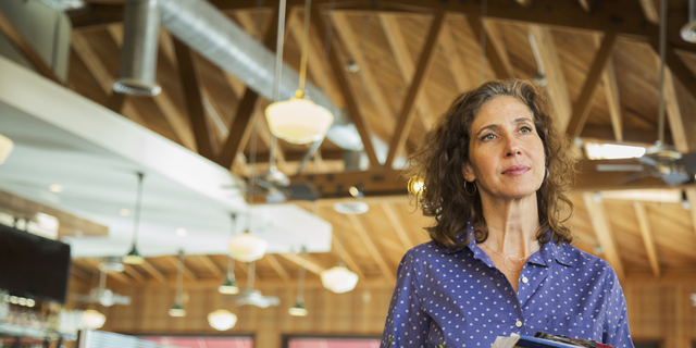 Pensive Caucasian woman holding paperwork in restaurant