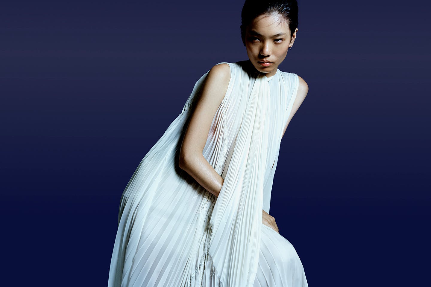 A model wearing a smocked, pleated dress made from a military surplus parachute.