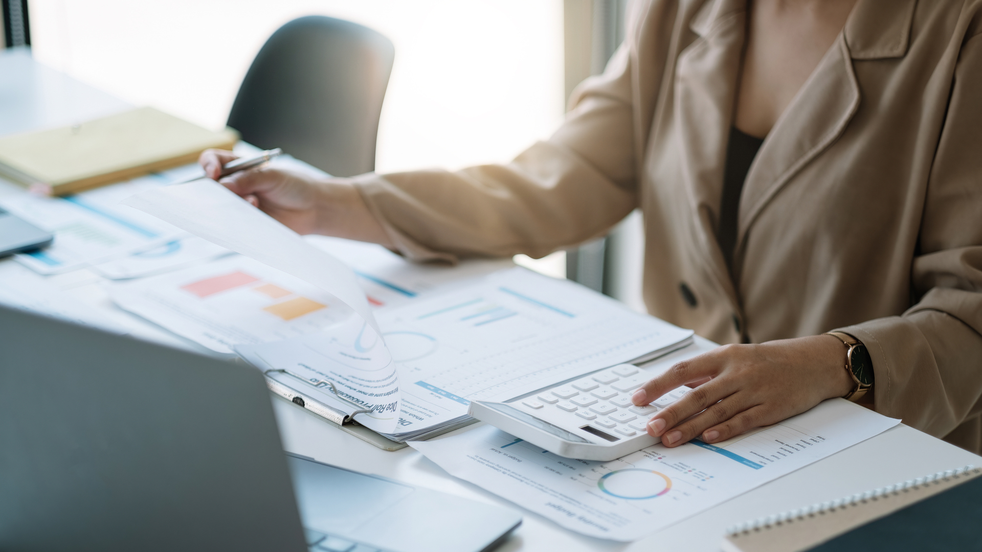 Close up woman planning budget, using calculator and laptop, reading documents, young female checking finances, counting bills or taxes, online banking services